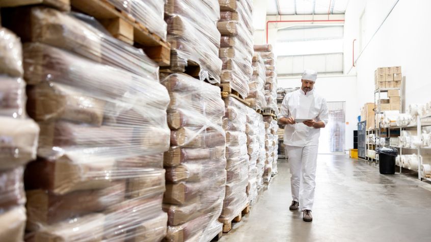 Warehouse employee reviewing palletized goods while evaluating the best sustainable packaging options for shipping and storage.
