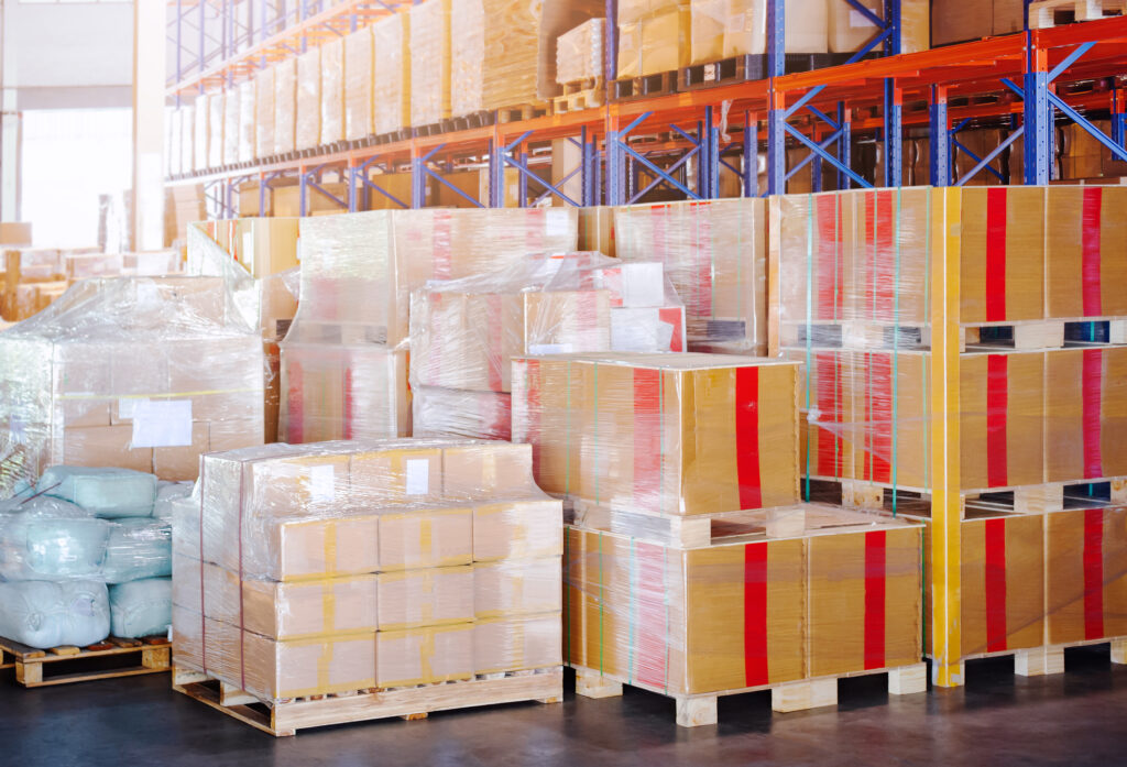 Package Boxes Wrapped Plastic Stacked on Pallets in Warehouse. Tall Shelve Storage Warehouse. Supply Chain, Supplies Shipment. Warehouse Shipping Logistics.